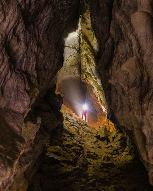 Caver standing in the Grand Gallery of Rat's Nest Cave near Canmore